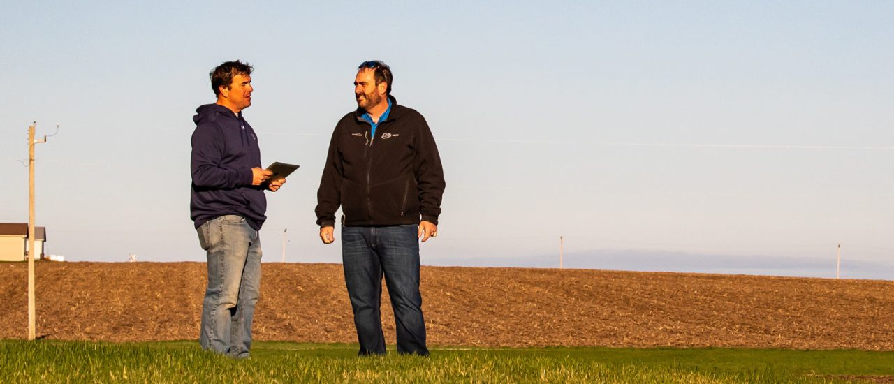 Two men talking while standing beside a harvested field